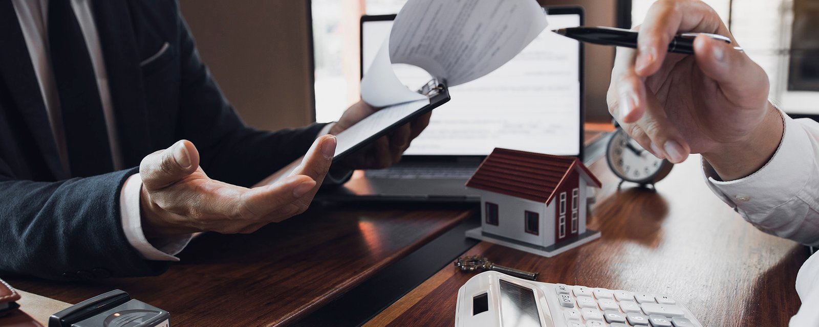 Business people home sales broker is using a pen pointing to the house model and describing the various components of th